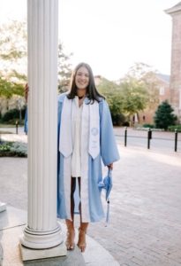 Bailey Pons poses in graduation regalia at the Old Well.